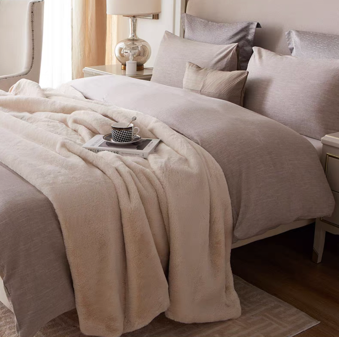 Beige reversible faux fur throw blanket layered on bed creating a luxurious and cozy atmosphere