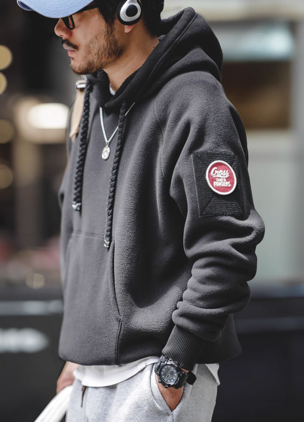 Side profile of RidgeLine Fleece Hoodie in black worn with headphones showing braided drawstrings and modern urban styling