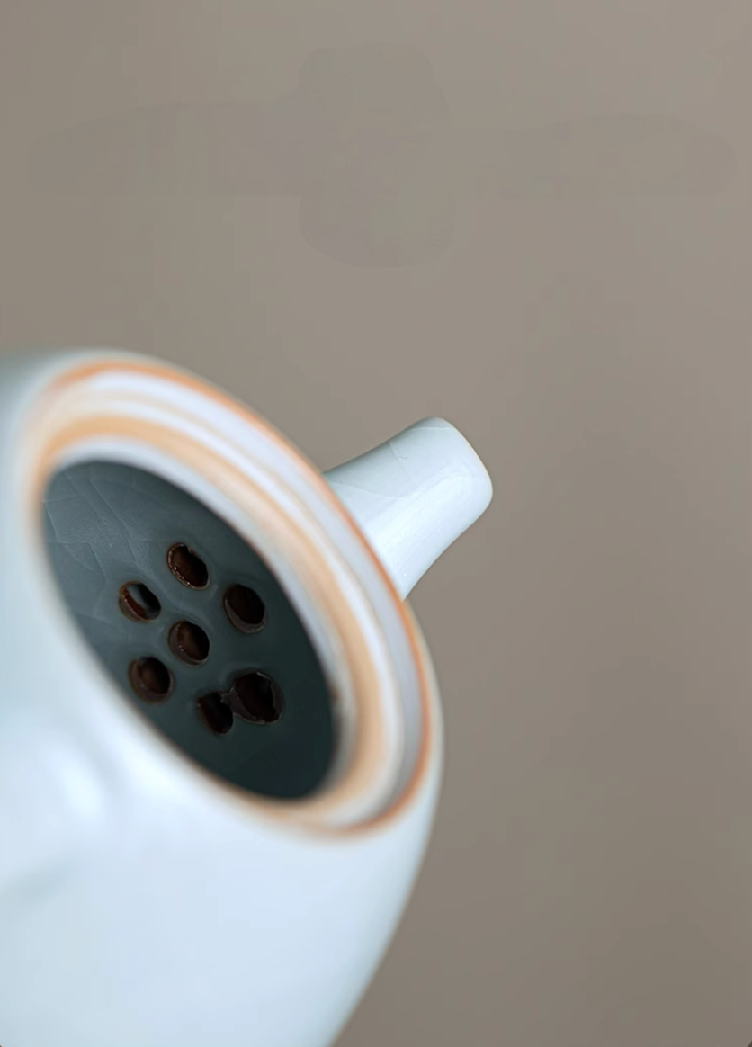 Close-up of Ru Kiln Celadon Mini Teapot in light blue showing built-in spout filter holes and inner ceramic detail