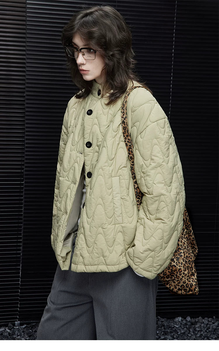 Side view of a Sage Green wave-quilted down jacket with stand collar, black buttons, and slit pocket