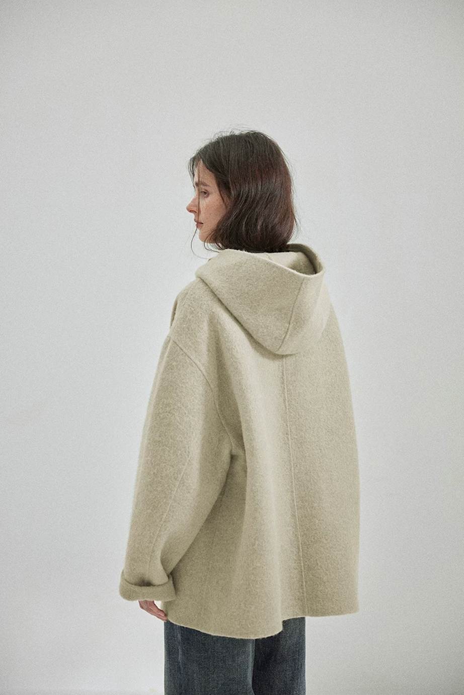 Back view of a Sage double-face wool coat showing the hood, center back seam, and dropped shoulders