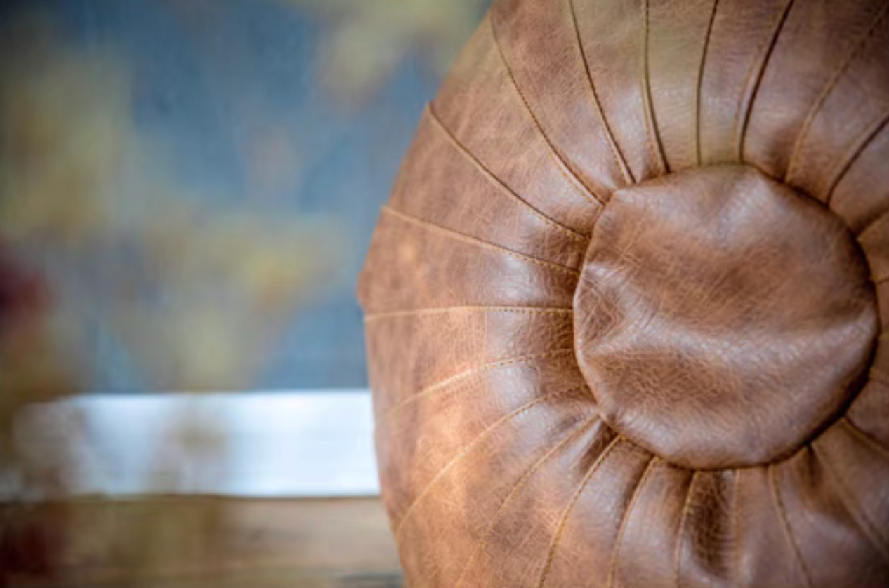 Side profile of camel Scandinavian round floor cushion showing pleated stitching and soft texture