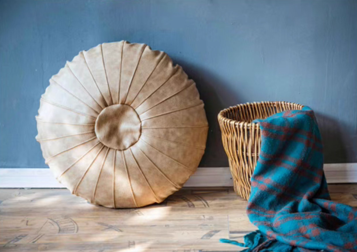 Ivory Scandinavian round floor cushion standing upright against wall next to a woven basket