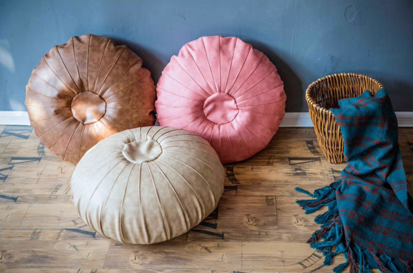 Scandinavian round floor cushions in camel, pink, and ivory displayed upright and on floor in a living space
