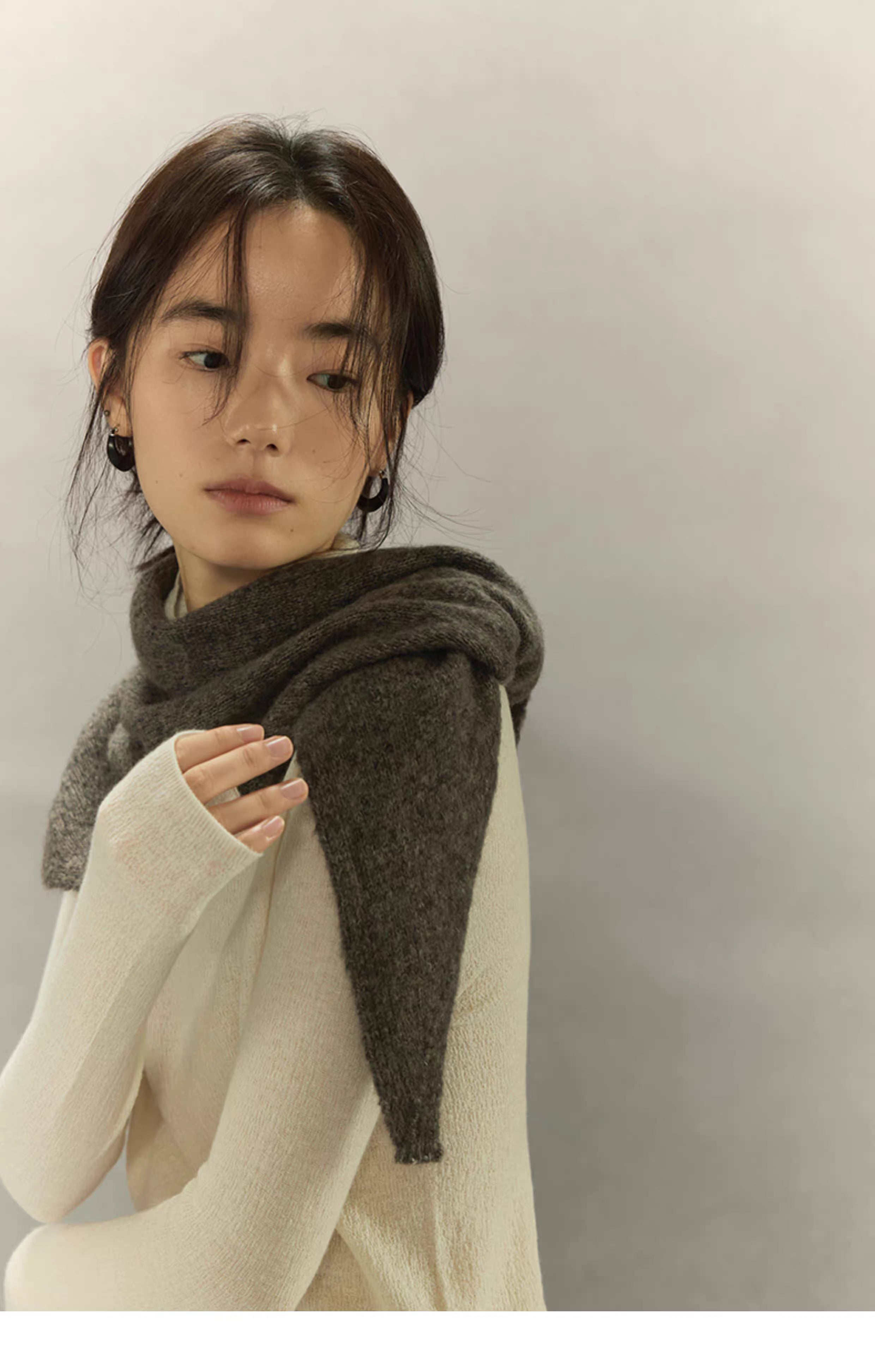 woman wearing charcoal brown knit scarf on cream sweater