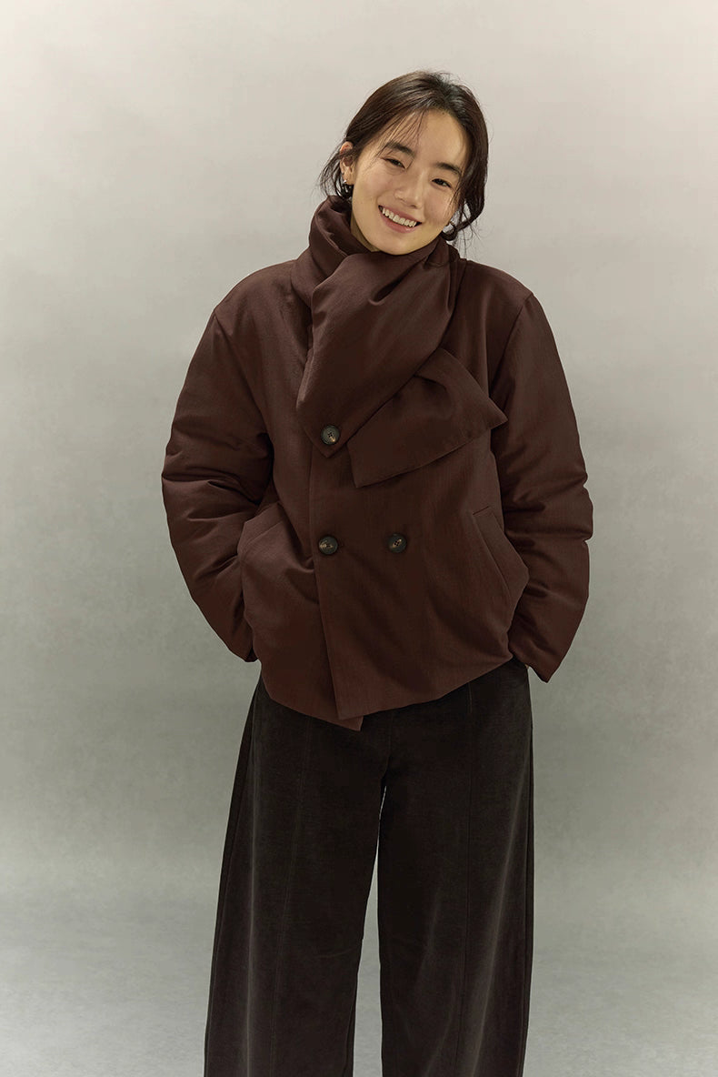 Scarf puffer jacket in dark coffee brown with hands in pockets and wrapped collar