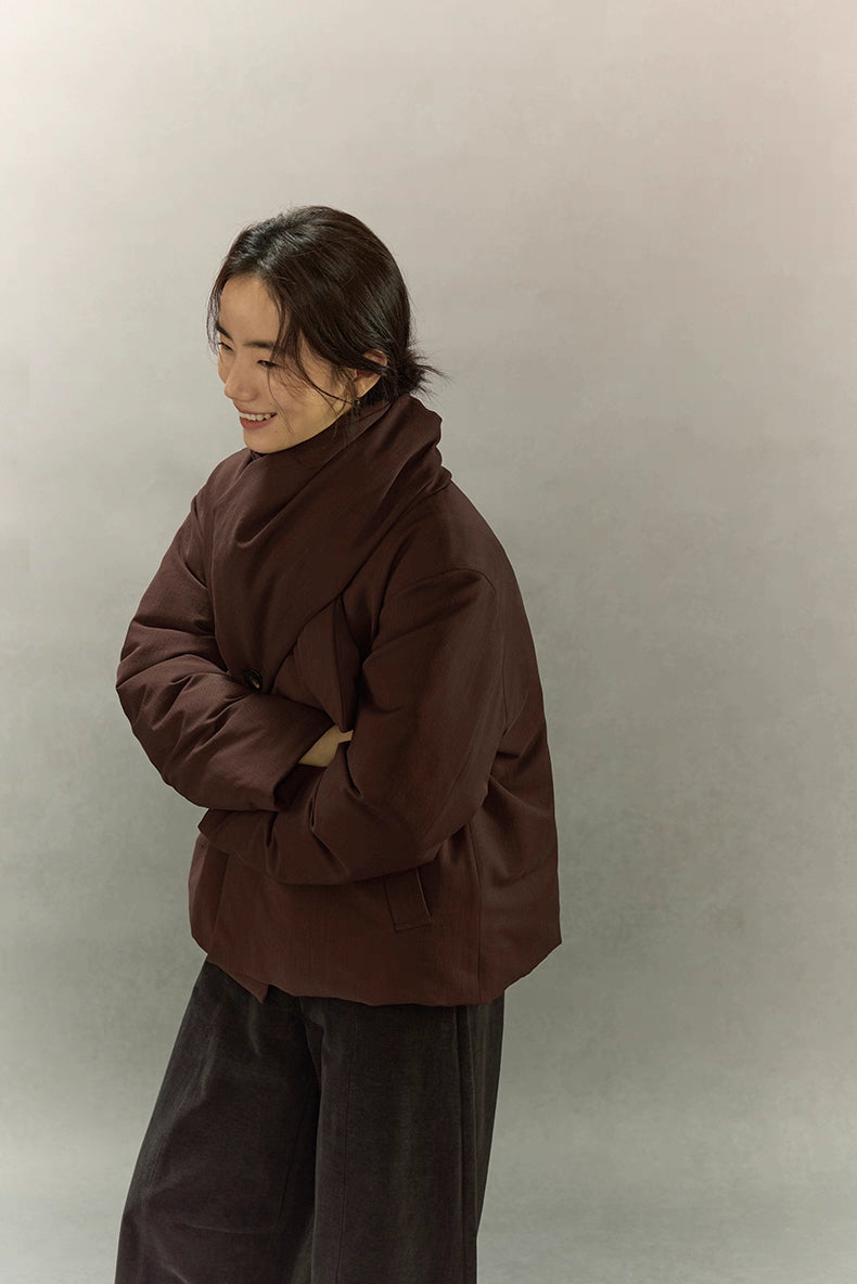 Woman laughing in dark coffee brown scarf puffer jacket with relaxed side pose