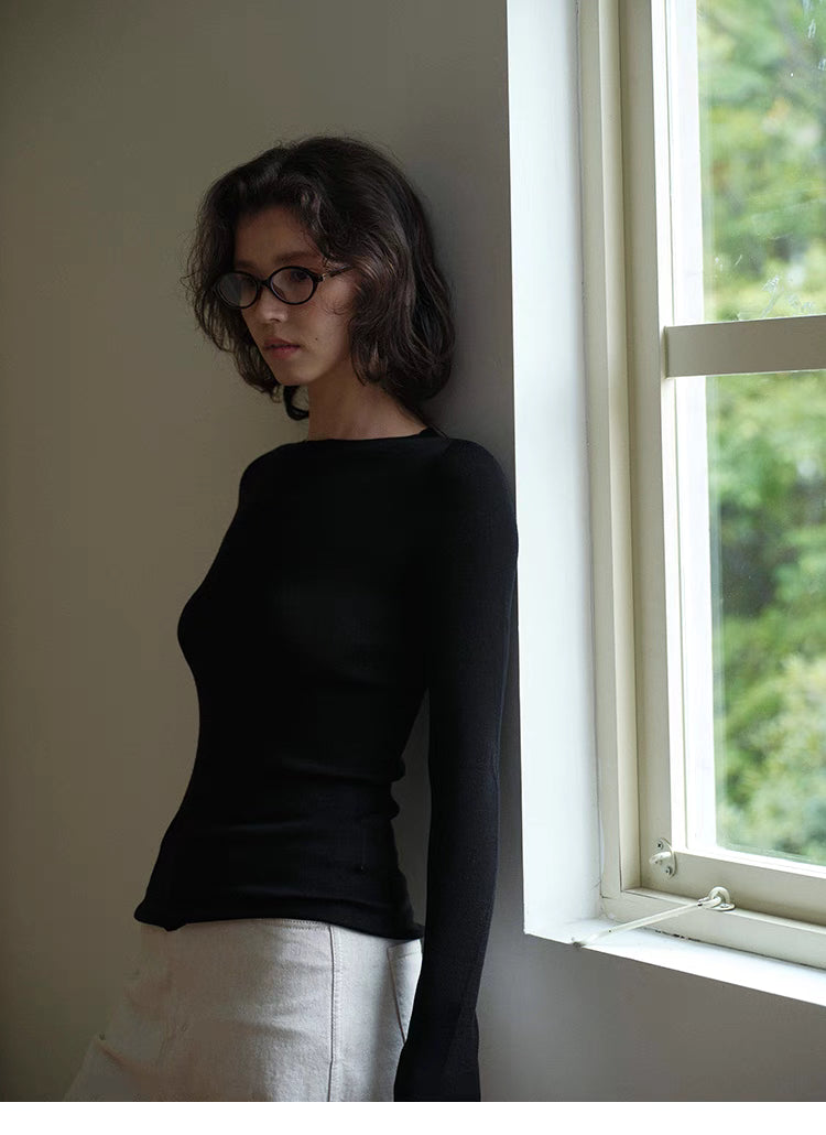 Side view of black merino sweater near window in natural light, emphasizing smooth texture and contour fit