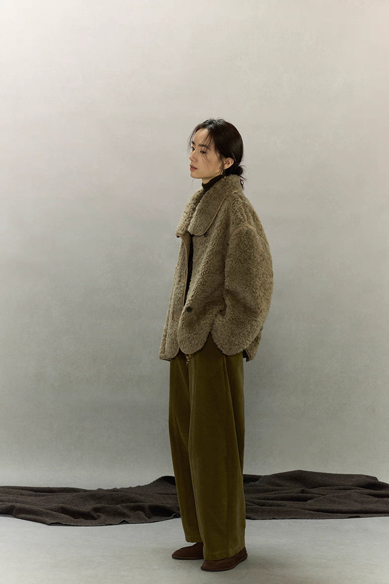 Full-body side view of woman wearing short sherpa wool jacket
