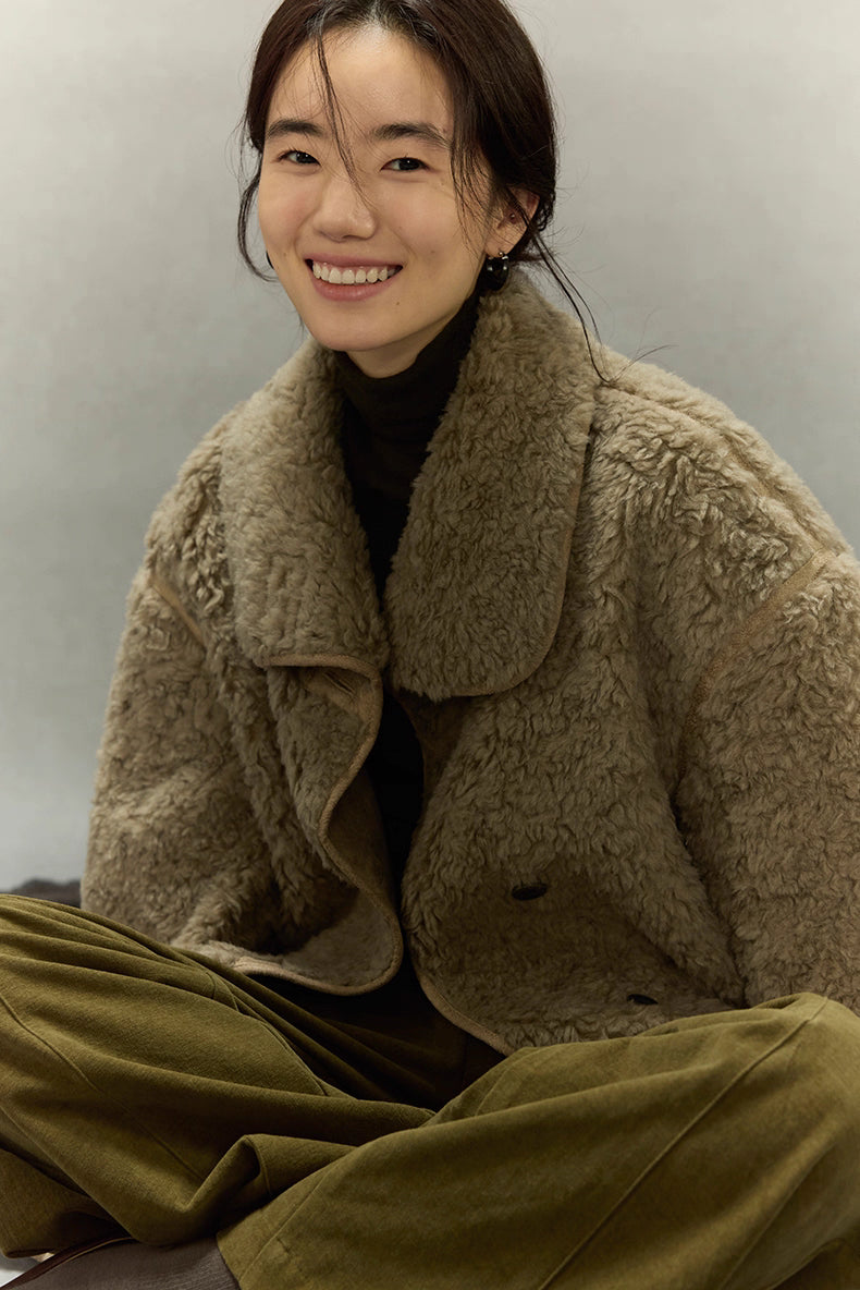 Woman sitting while wearing sherpa wool jacket with soft oversized collar