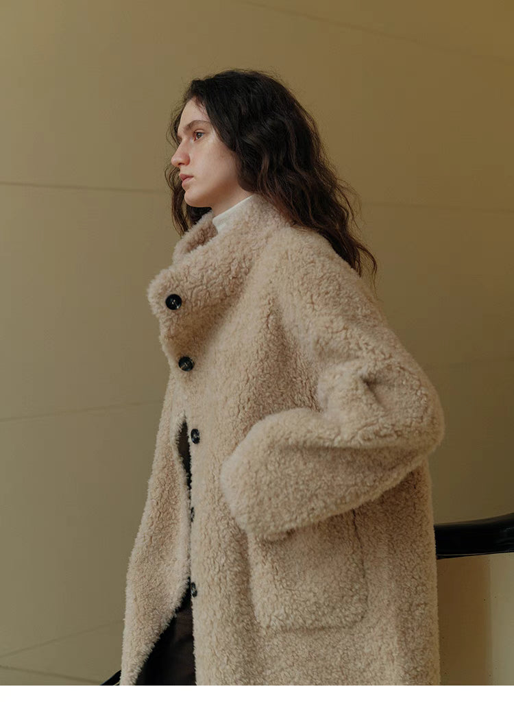 Side profile of Sierra Luxe Shearling Coat in beige apricot highlighting stand collar, patch pocket detail, and plush wool fabric