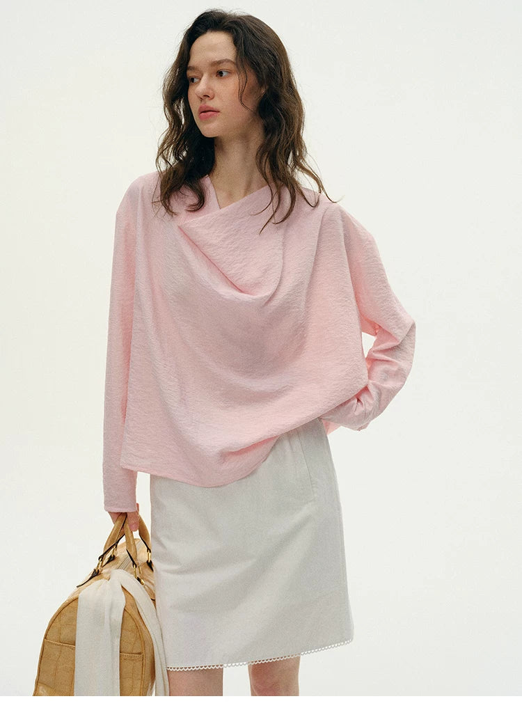 Woman wearing pink silk cowl neck top with light gray skirt, front view