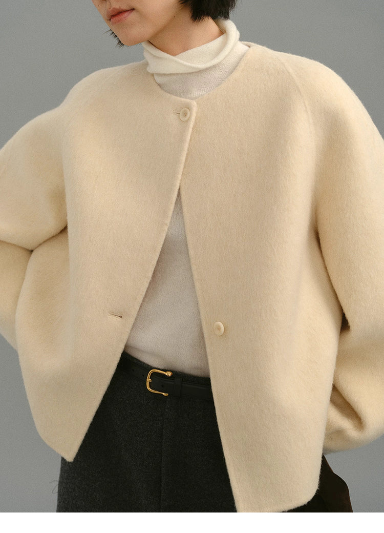 Front detail of cream cocoon jacket highlighting round neckline and button closure