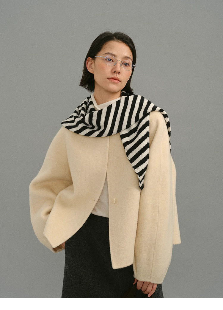 Cream cocoon jacket styled with black and white striped scarf around shoulders