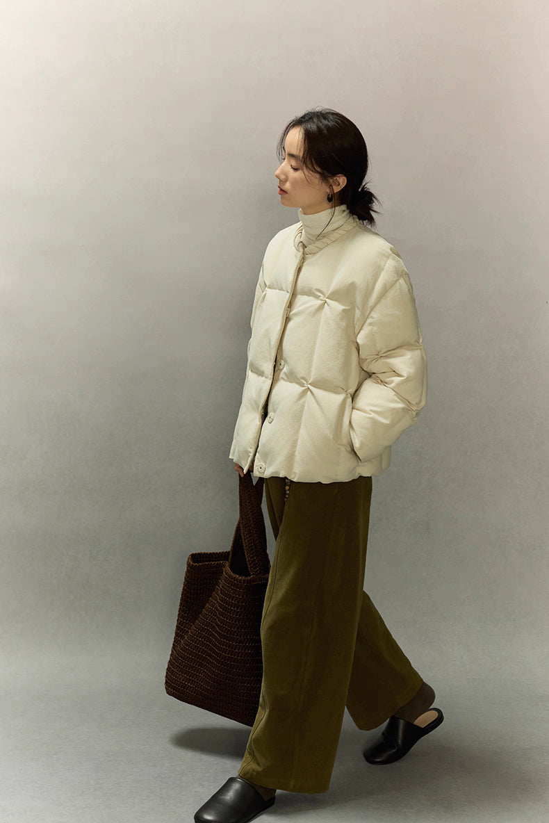 Side profile of model walking in cream beige SoftCloud down jacket, showing short length and easy movement.