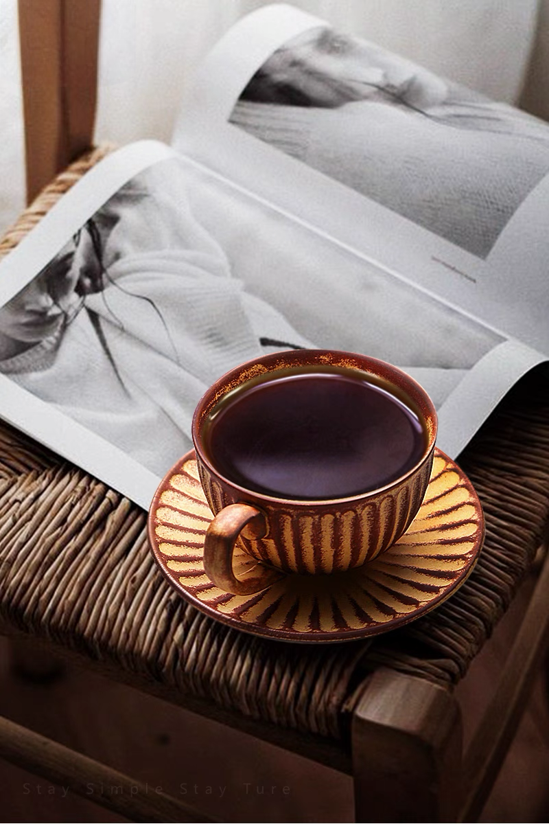 Yellow striped ceramic cappuccino cup filled with coffee placed on woven chair with magazine creating relaxed lifestyle scene