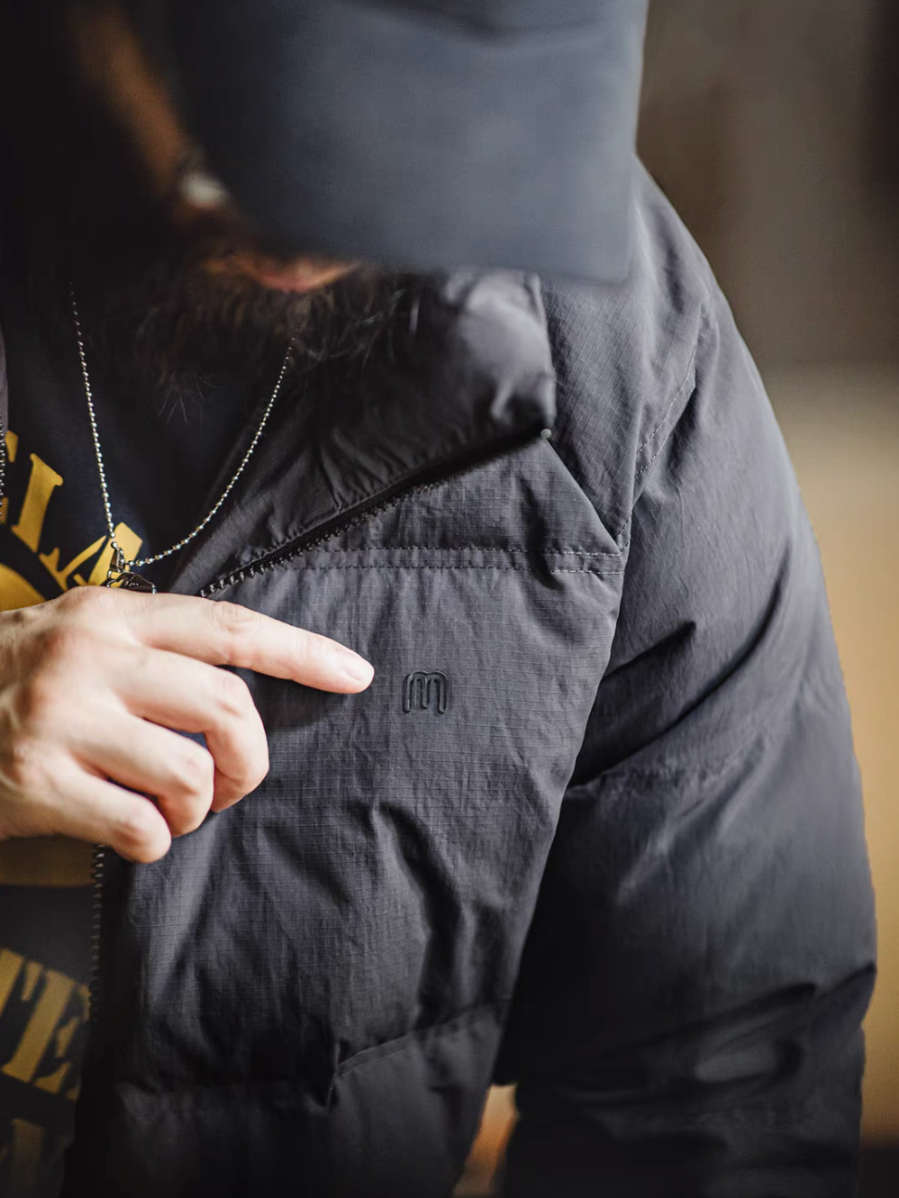 Detailed close-up of SummitShield down jacket in dark gray highlighting chest logo, fabric texture, and premium stitching