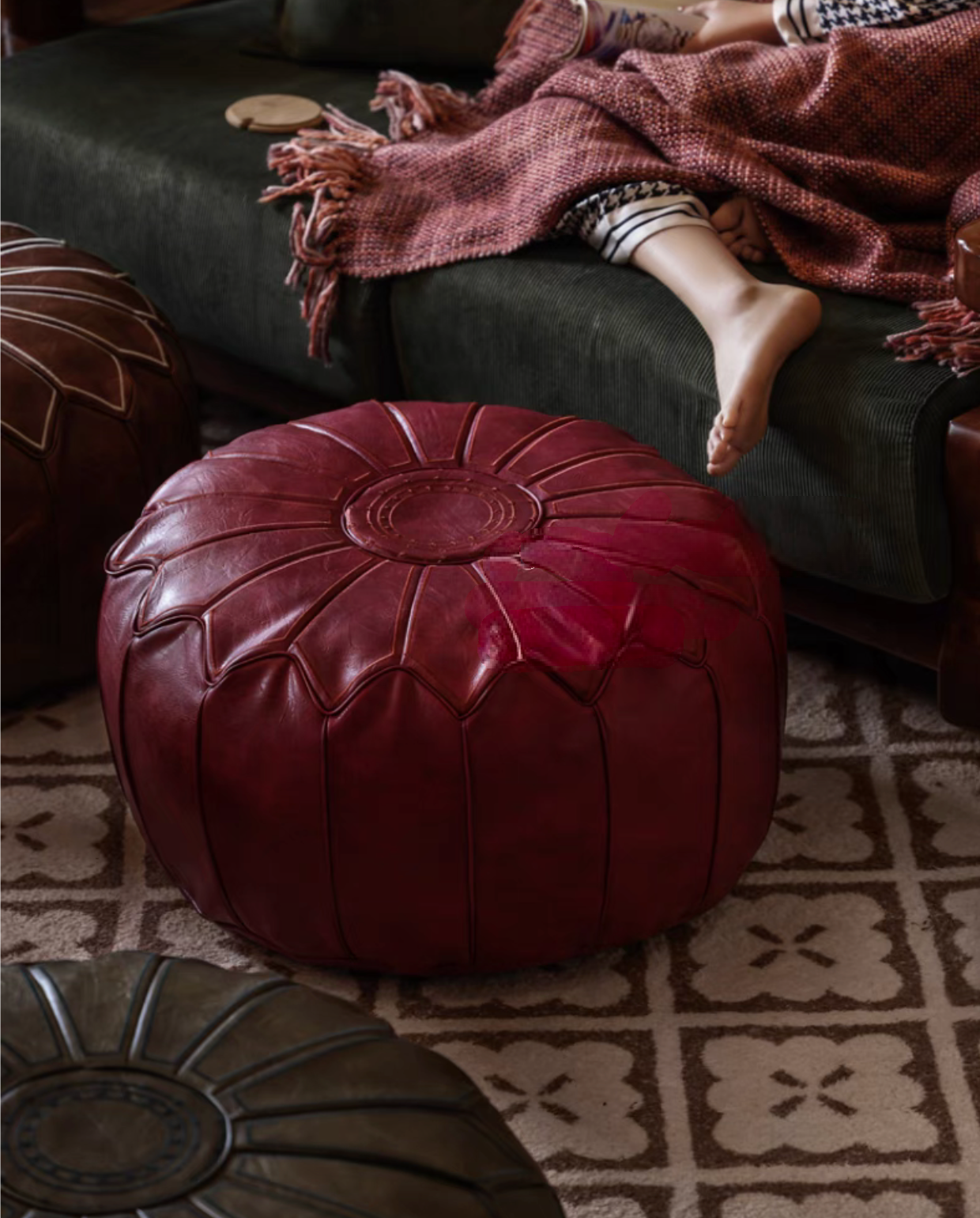 Dragon fruit red faux leather pouf ottoman placed on rug near sofa in a cozy living room setting