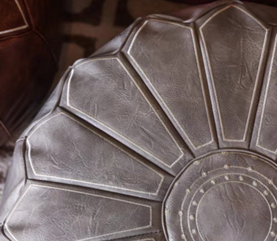 Close-up of gray faux leather pouf ottoman showing detailed stitching and textured surface
