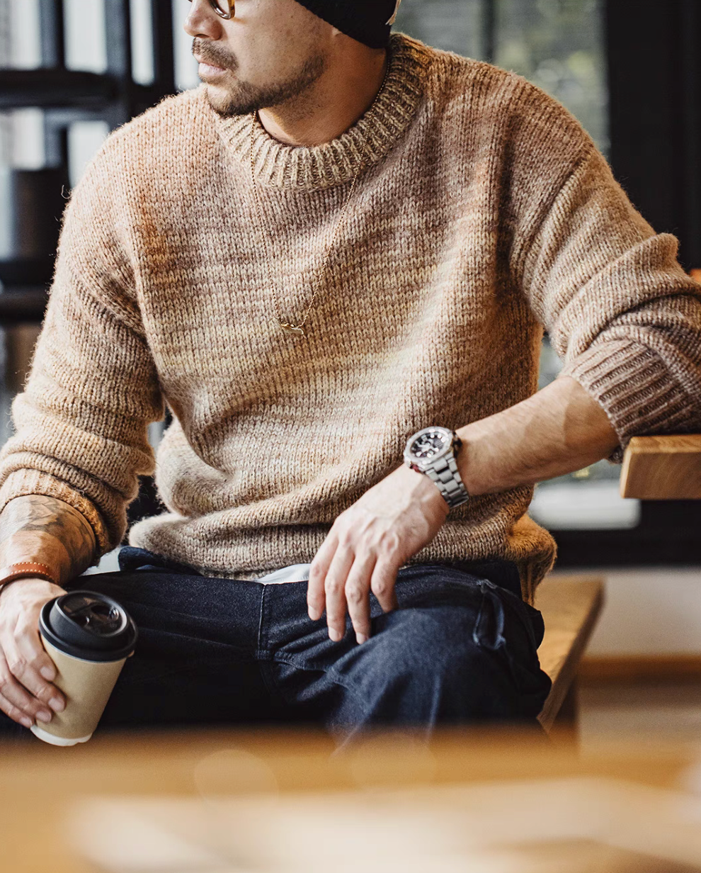 Man wearing Sunset Drift Knit Sweater in Tea Brown holding coffee showcasing gradient knit texture relaxed fit and warm fall styling