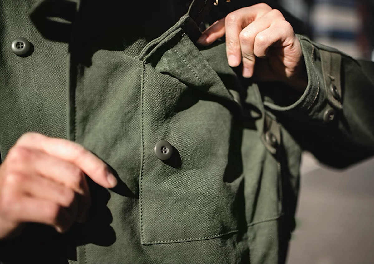 Model using chest pocket of Swedish military motorcycle jacket – functional workwear design.