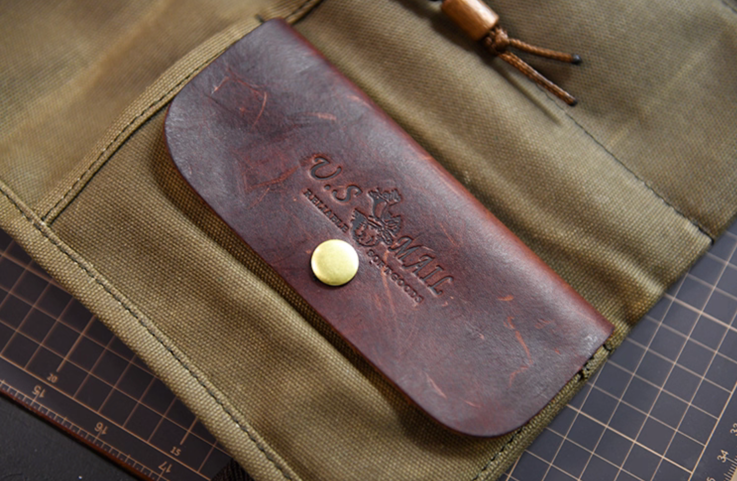 Close-up of Field Companion’s full-grain leather U.S. Mail pocket with brass snap.