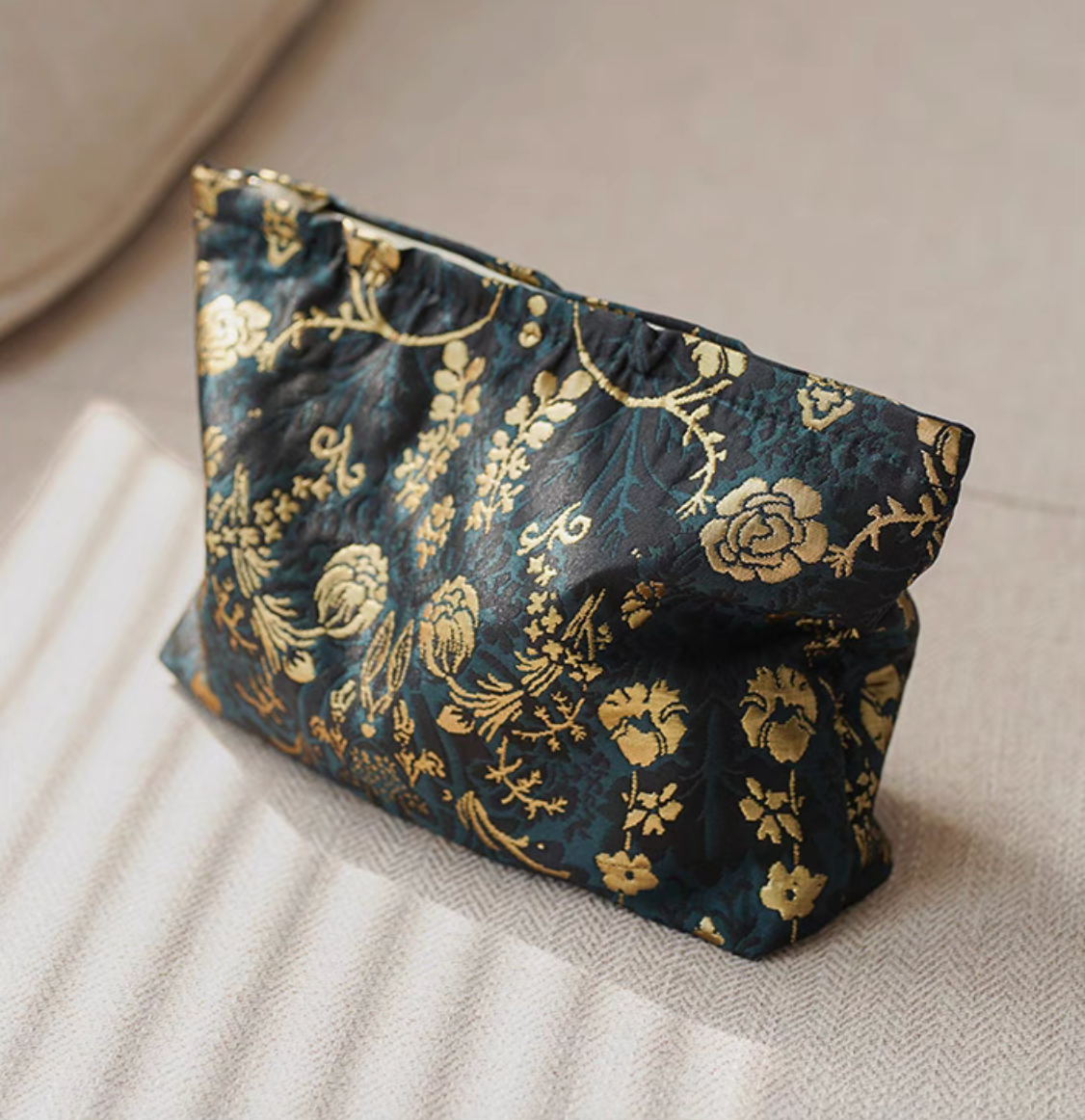Side angle view of Timeless Elegance Portable Makeup Bag in dark green and gold pattern showing structured shape and stitching detail