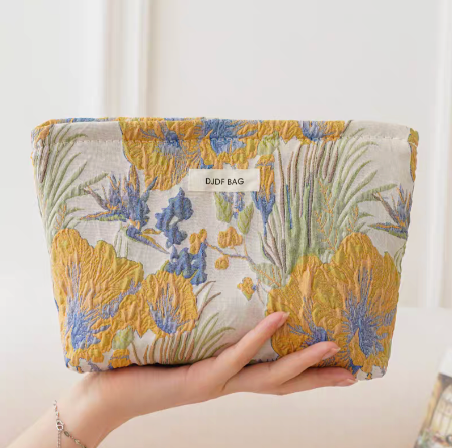 Timeless Elegance Portable Makeup Bag in embossed gold yellow floral pattern held in hand showing raised textured design