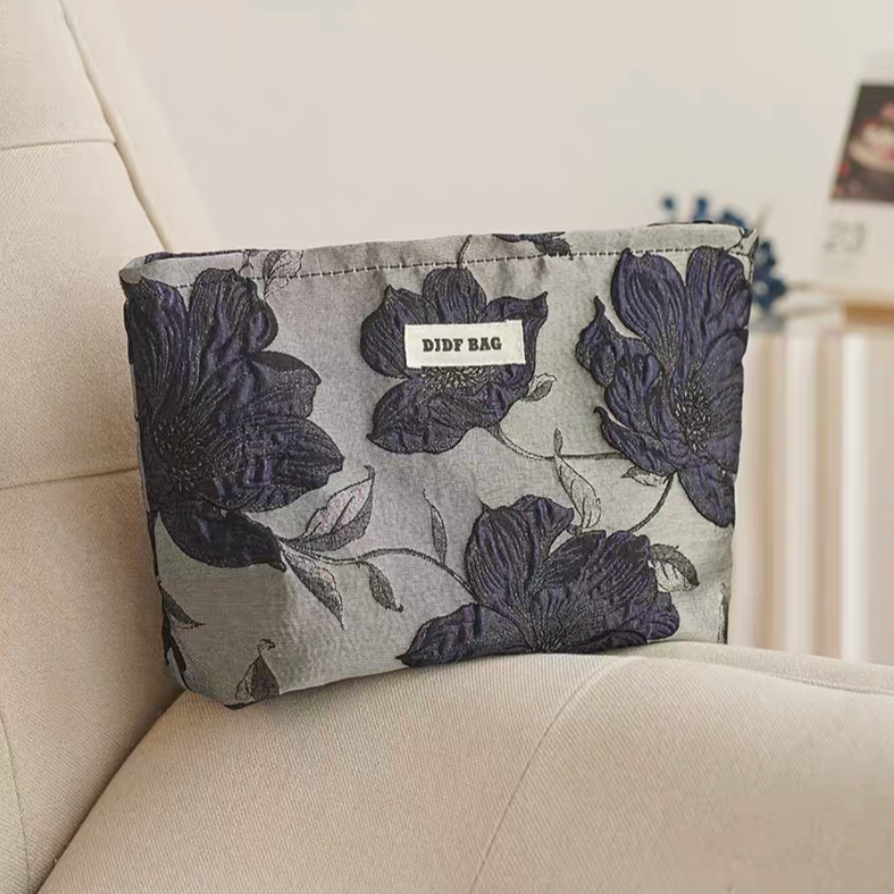 Timeless Elegance Portable Makeup Bag in navy blue large flower pattern placed on sofa with bold floral design