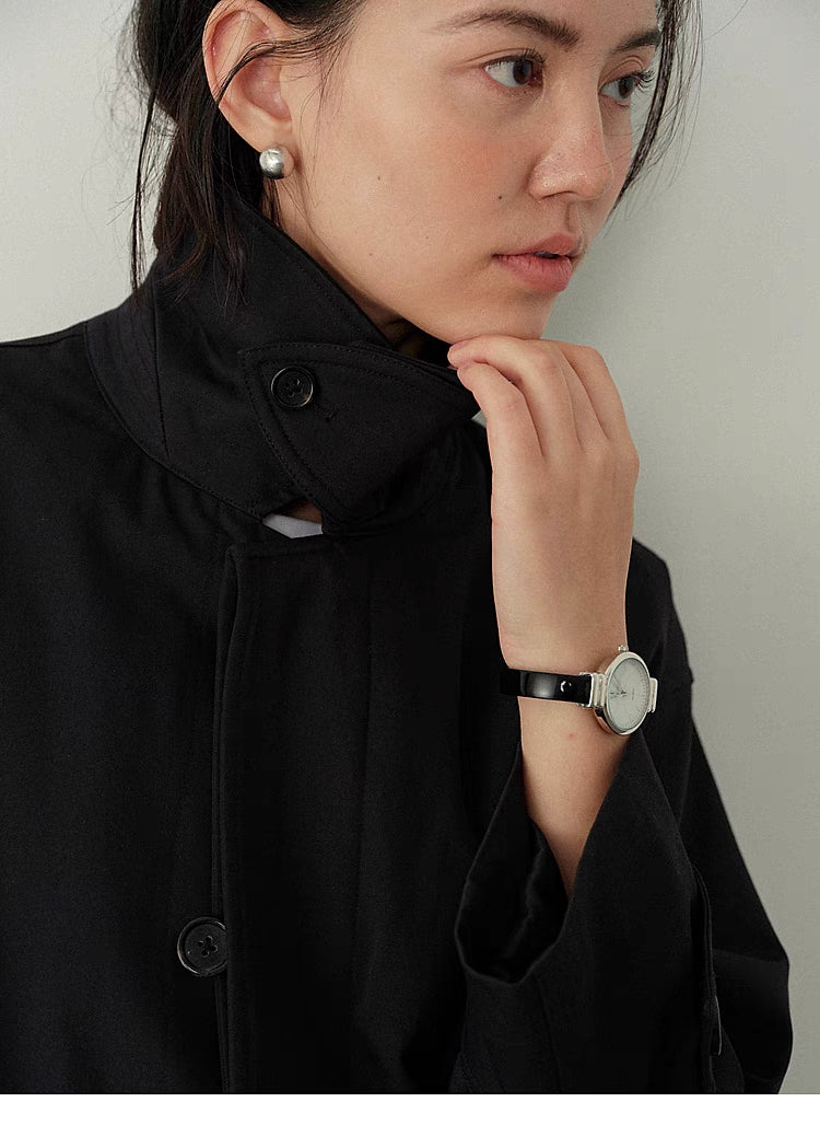 Close-up of Black Timeless Trench Coat showing convertible stand collar, button detail and smooth fabric texture