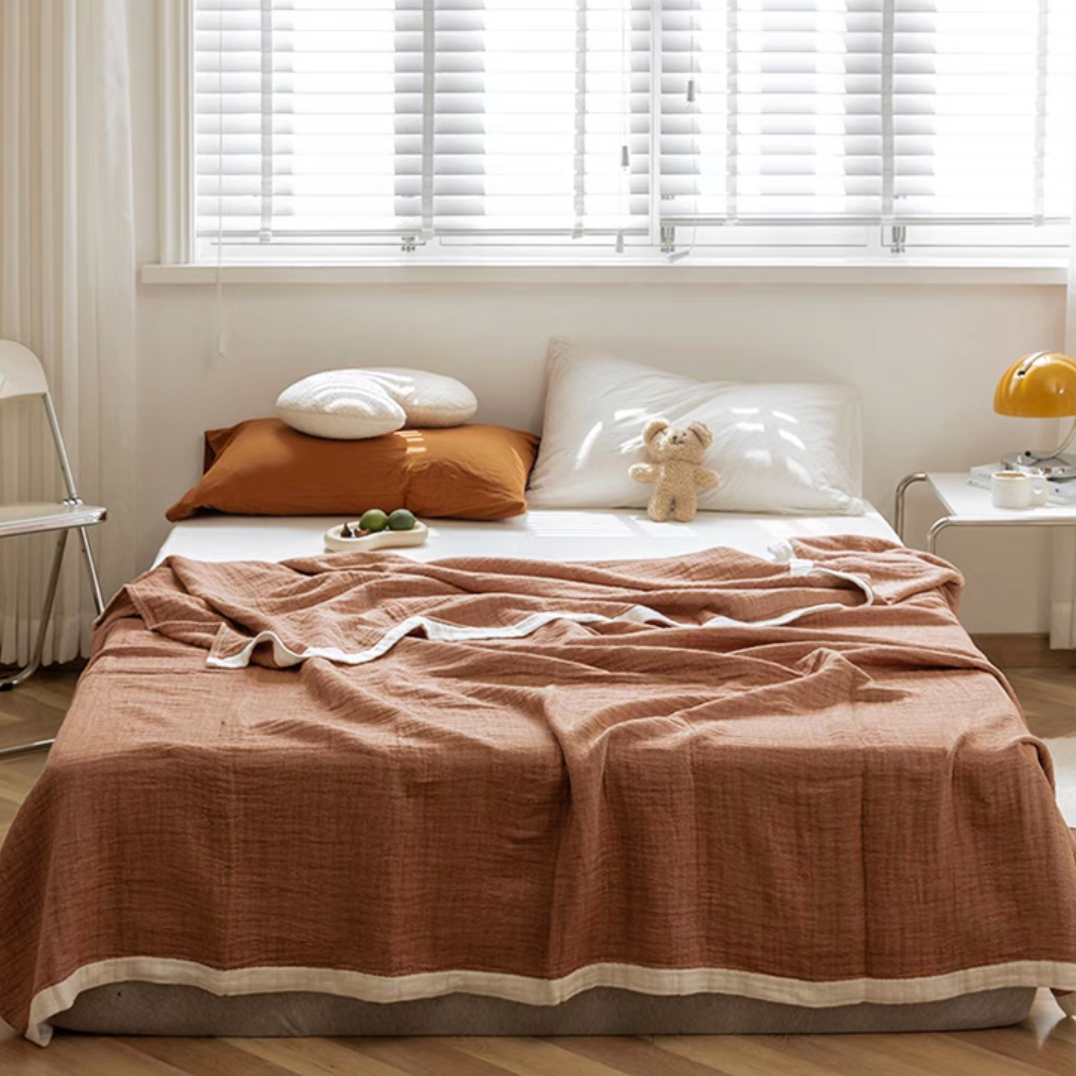 Light coffee color ripple gauze cotton quilt with zigzag edge styled on bed with warm neutral bedding.