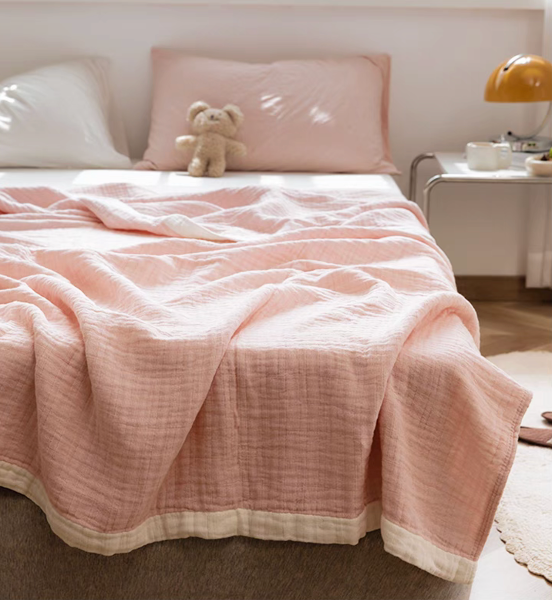 Light pink organic cotton ripple gauze quilt styled on modern bed with soft natural lighting.