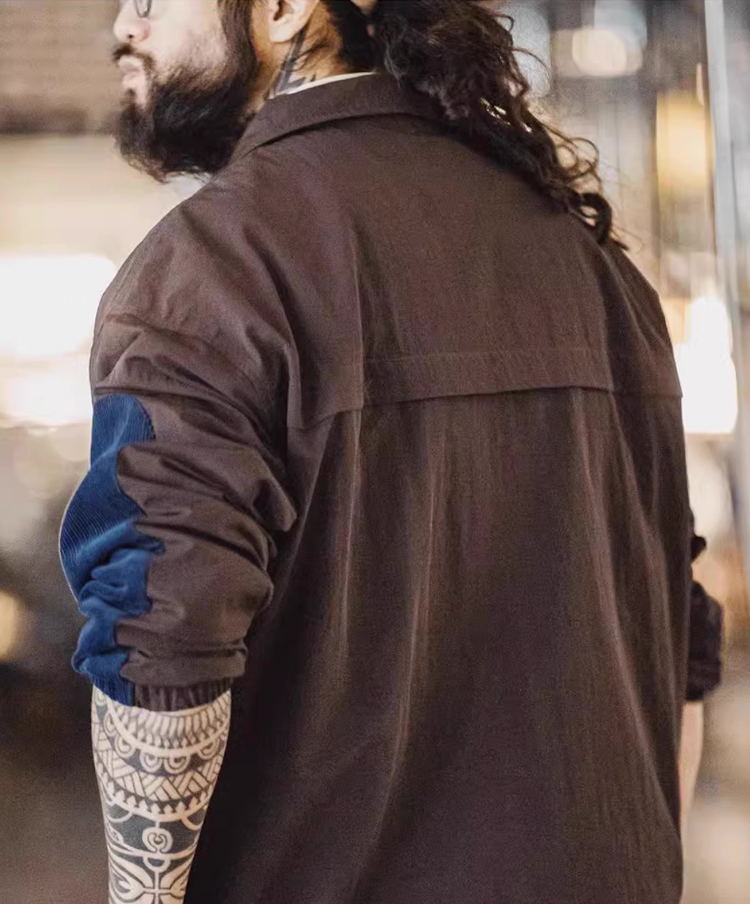 Back view of model wearing URBANCORE half-zip nylon jacket, featuring trench-inspired back flap and relaxed urban fit.