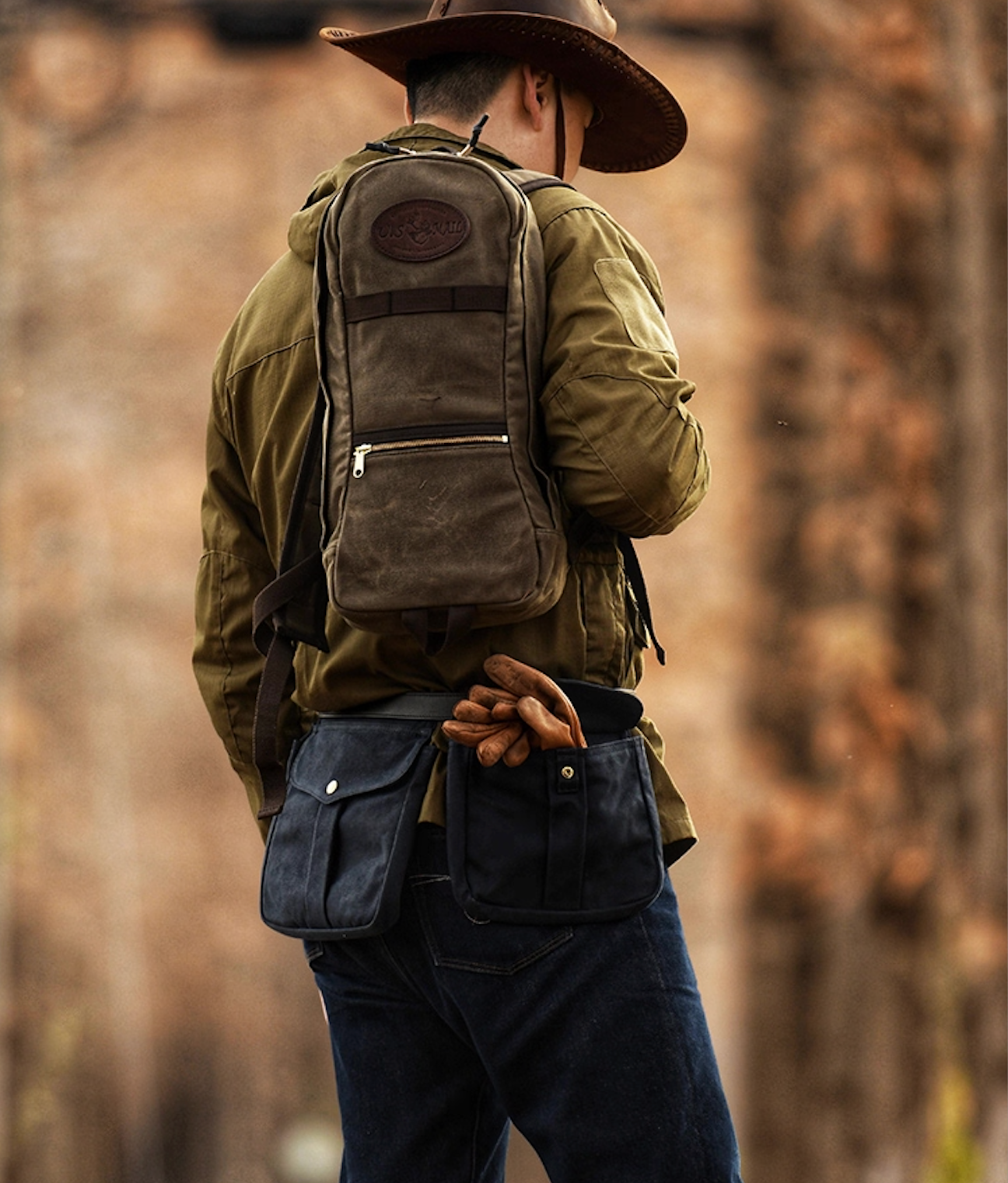 Man hiking with U.S. Mail waxed canvas backpack and cowboy hat on forest trail.