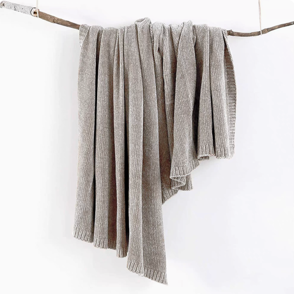 Gray vertical rib chenille knit solid throw blanket hanging over a wooden branch