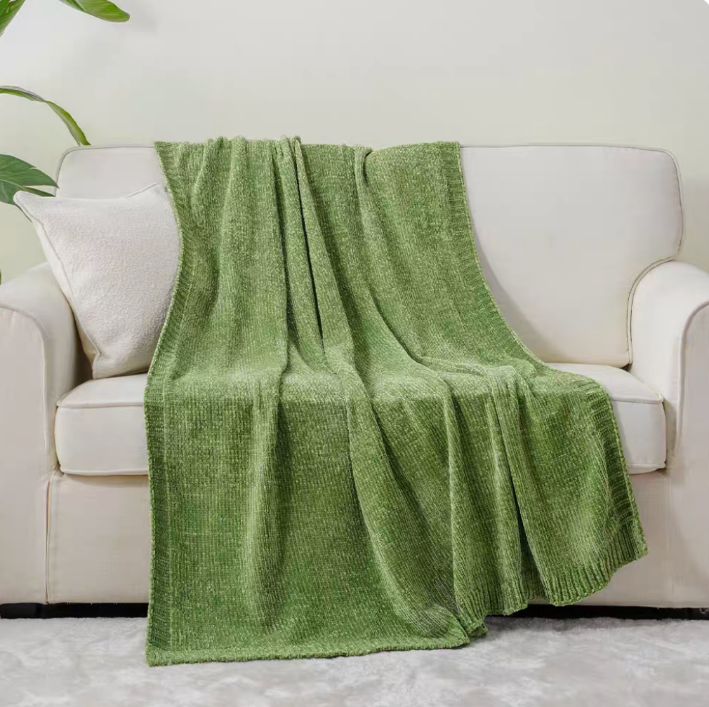 Green vertical rib chenille knit solid throw blanket draped over a white sofa