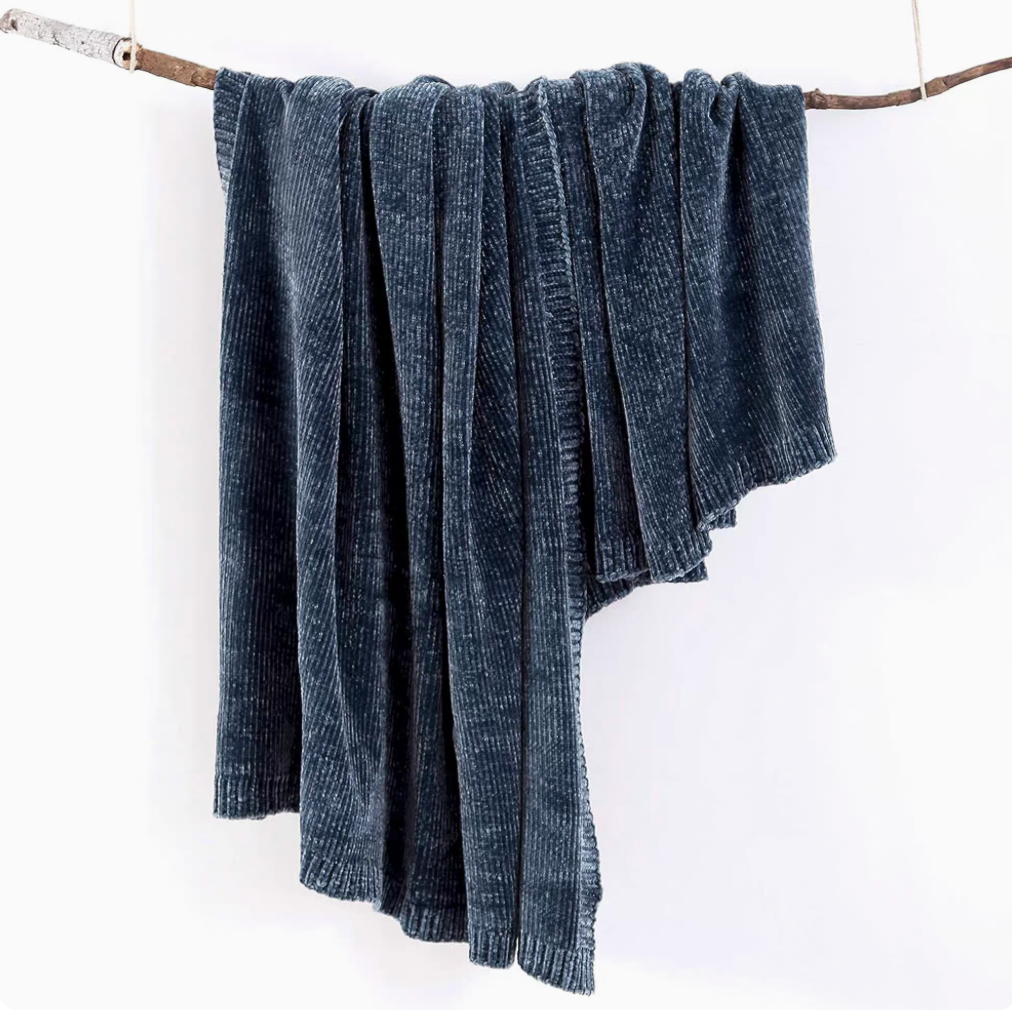Navy blue vertical rib chenille knit solid throw blanket hanging over a wooden branch
