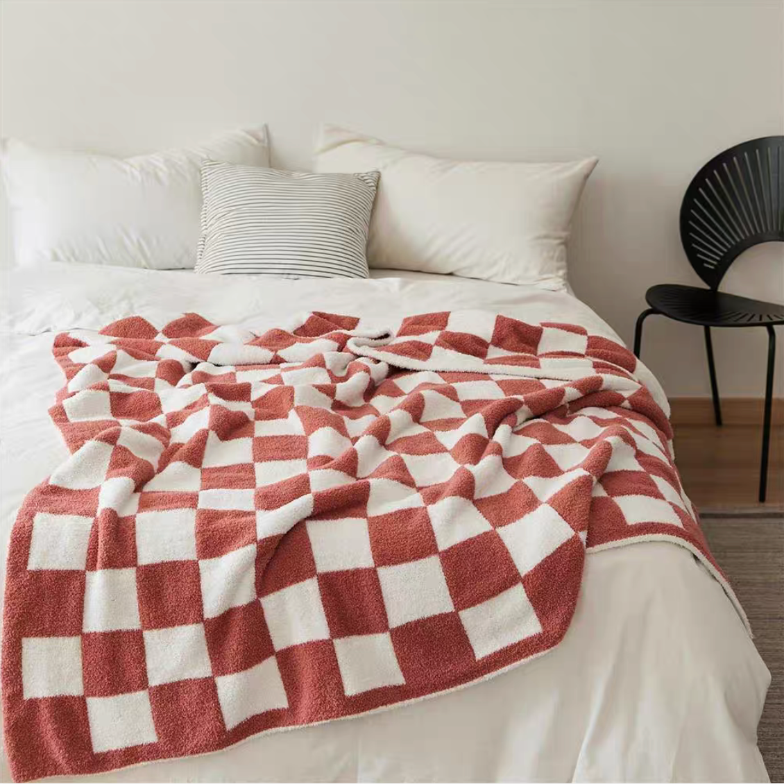 Watermelon red checkered blanket spread across bed with pillows creating warm and cozy bedroom atmosphere