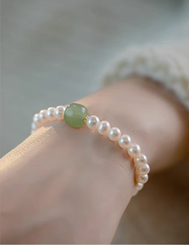 Close-up of central jade bead with pearl accents, highlighting smooth texture and natural color contrast.