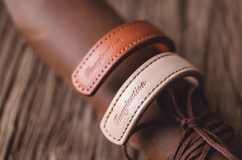 Dark brown and pink leather cuff bracelets wrapped around leather accessory showing curved shape and stitching detail
