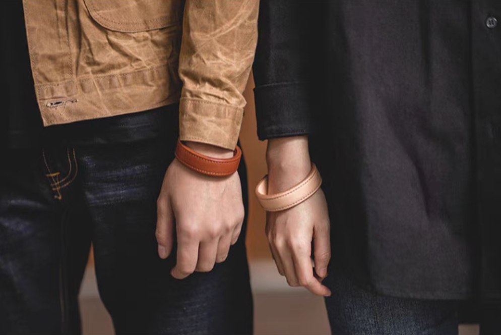 Dark brown and pink leather cuff bracelets worn on wrists paired styling front view