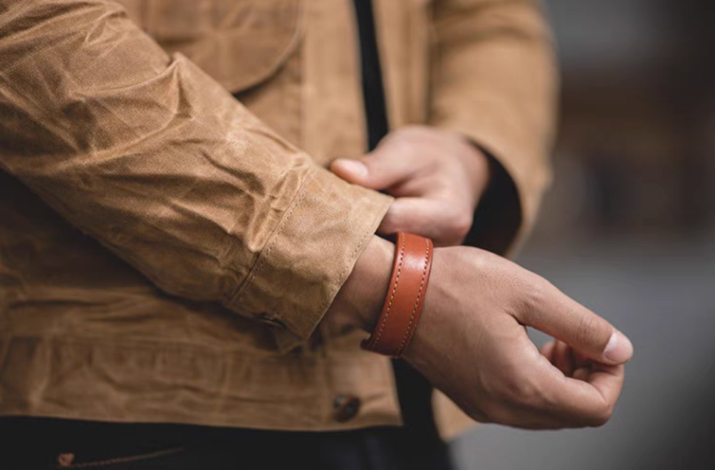 Dark brown leather cuff bracelet worn on wrist close-up showing smooth leather texture and stitching