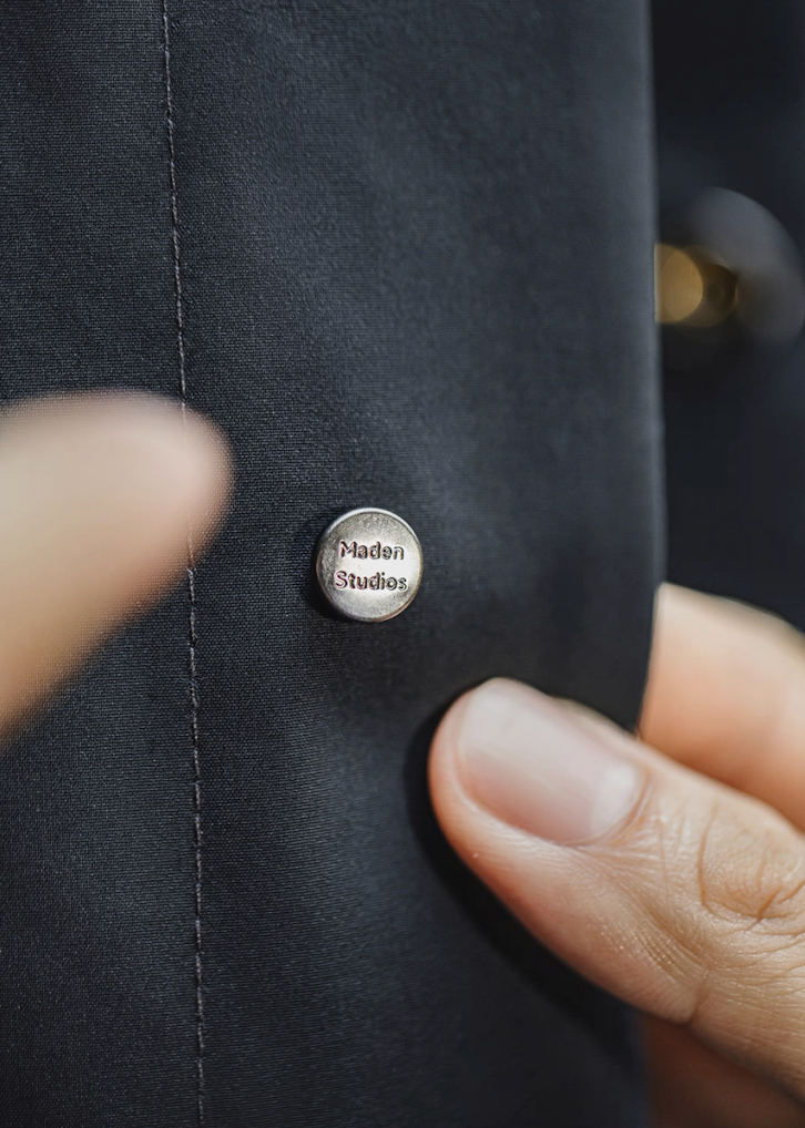 Close-up metal snap button detail on waterproof Mac coat
