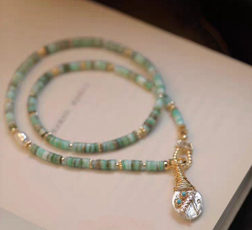 Whimsical Baroque Pearl and Shell Choker with turquoise beads and baroque pearl pendant displayed on surface