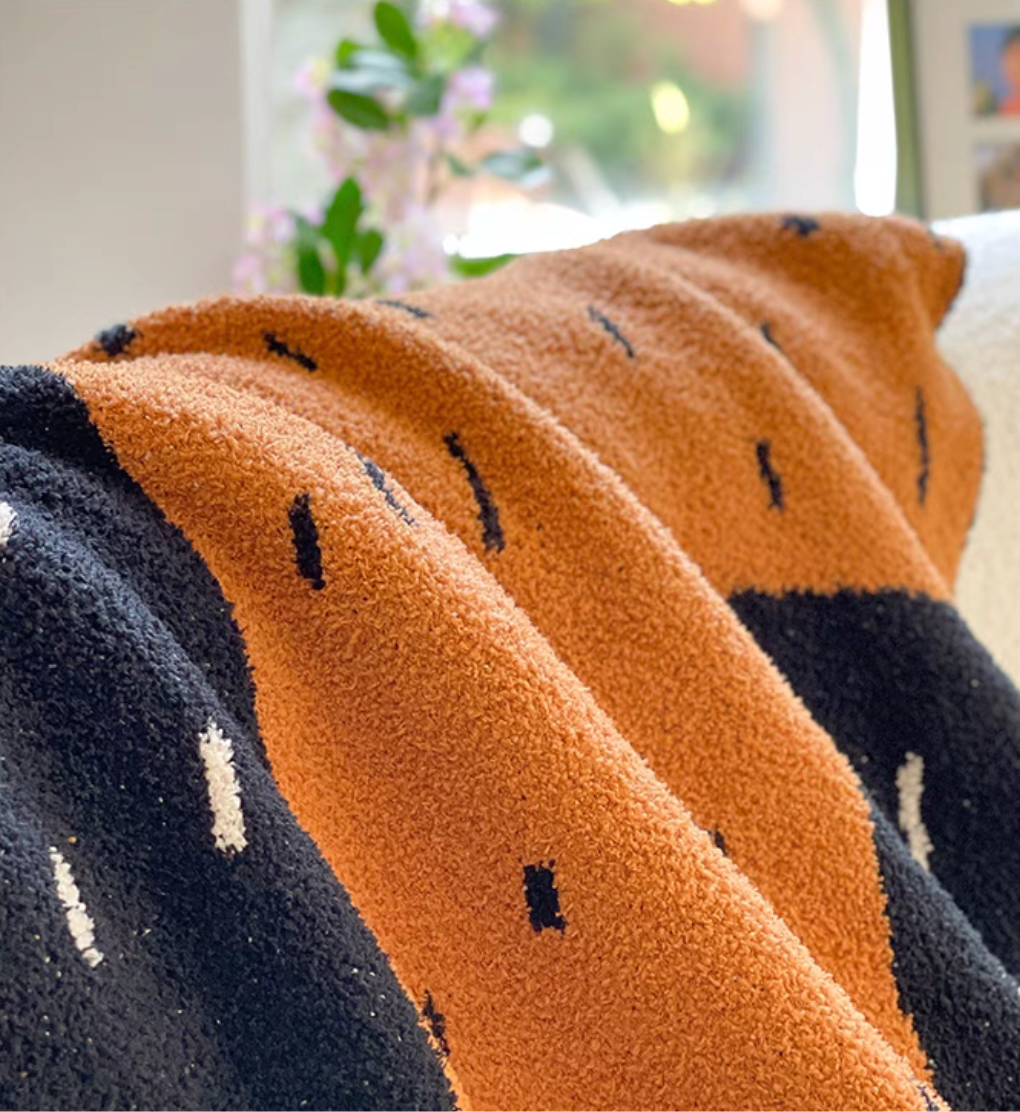 Close-up of wild cactus throw blanket highlighting soft high-density weave texture in orange and black sections
