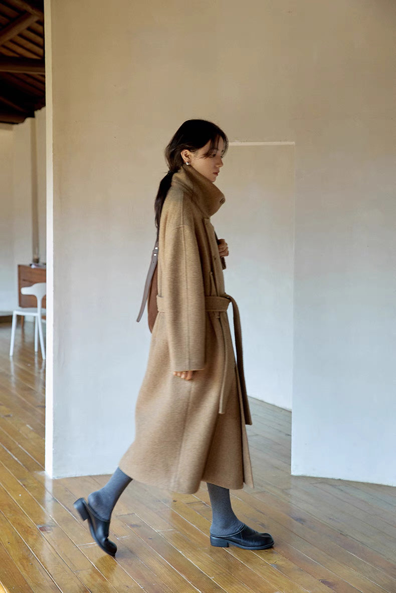 Woman walking in khaki long Willow Lane Wool Coat in side motion view, highlighting flowing hem, belted waist, and relaxed elegant movement