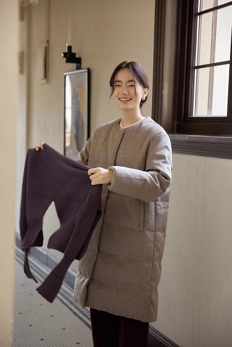 woman holding knit sweater while wearing wool-blend long down coat