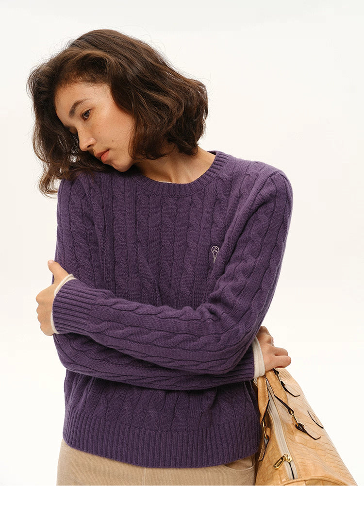 Close-up of deep purple wool cable sweater showing embroidered key logo
