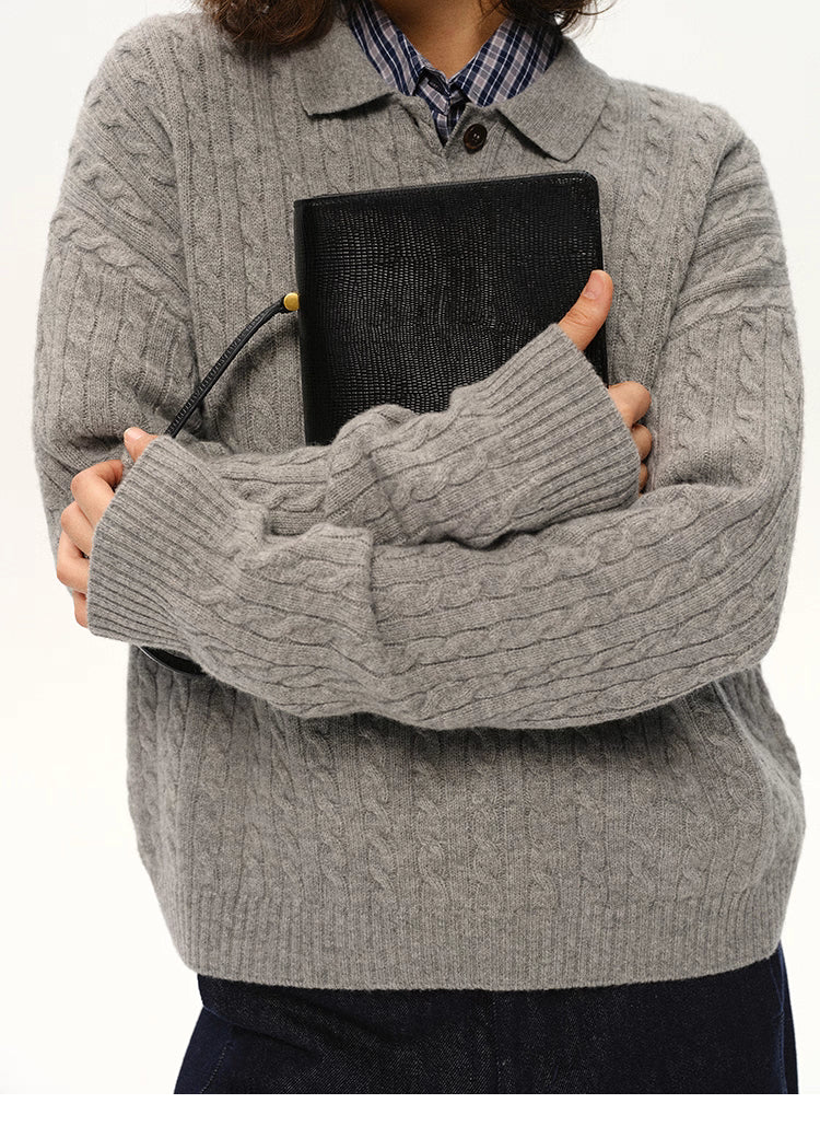 Close-up of grey cable-knit wool polo sweater showing sleeve texture and ribbed cuffs