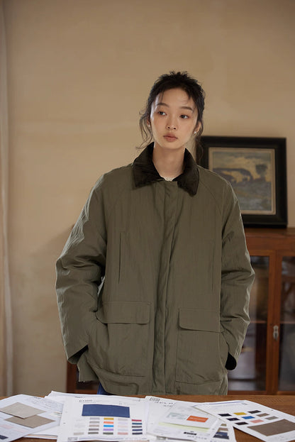Model wearing army green heritage outdoor down jacket with corduroy collar indoors.
